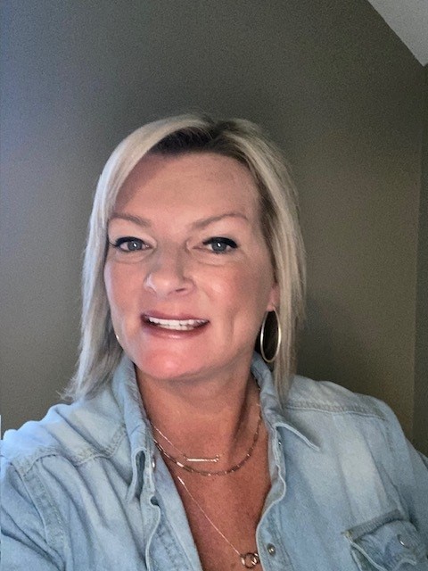 Smiling woman with blonde hair in a light blue shirt.
